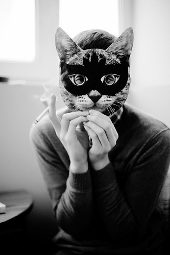 Person holding a cat mask in front of their face.