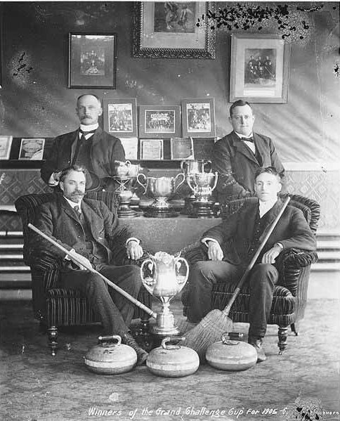 Curling team sitting around trophies, Dawson, Yukon Territory
