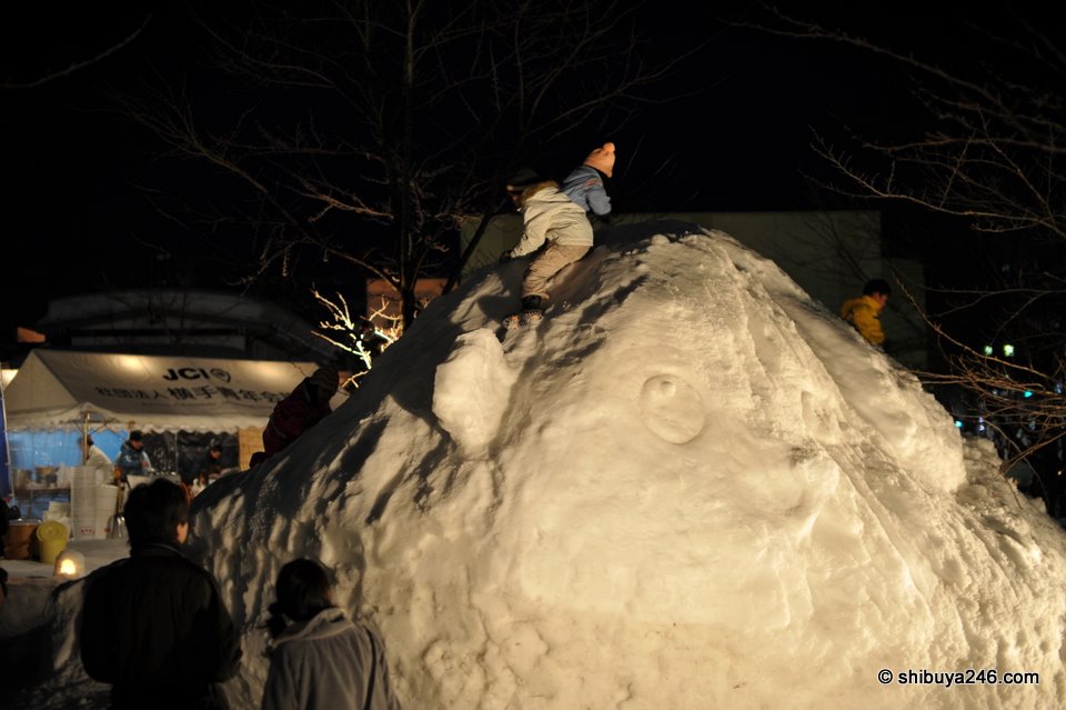 Some of the kids took turns sliding down the large Mameshiba snow statute.