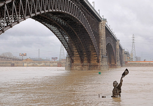Riverfront in Saint Louis, Missouri, USA - bronze sculpture Captain's Return and Eads Bridge at high water