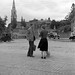 Man talking to woman in cobbled square, church visible in background, Co. Dublin