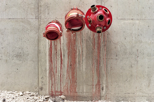fresh red paint, from stand pipes, running down the walls of a building under construction in Chicago's south loop