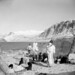 A group of Inuit standing outside near their tupiit (tents), showing Pangnirtung Fiord and Mount Duval in the background... / Un groupe d’Inuits debout, dehors, près de leurs tentes, en arrière-plan le fjord Pangnirtung et le mont Duval...